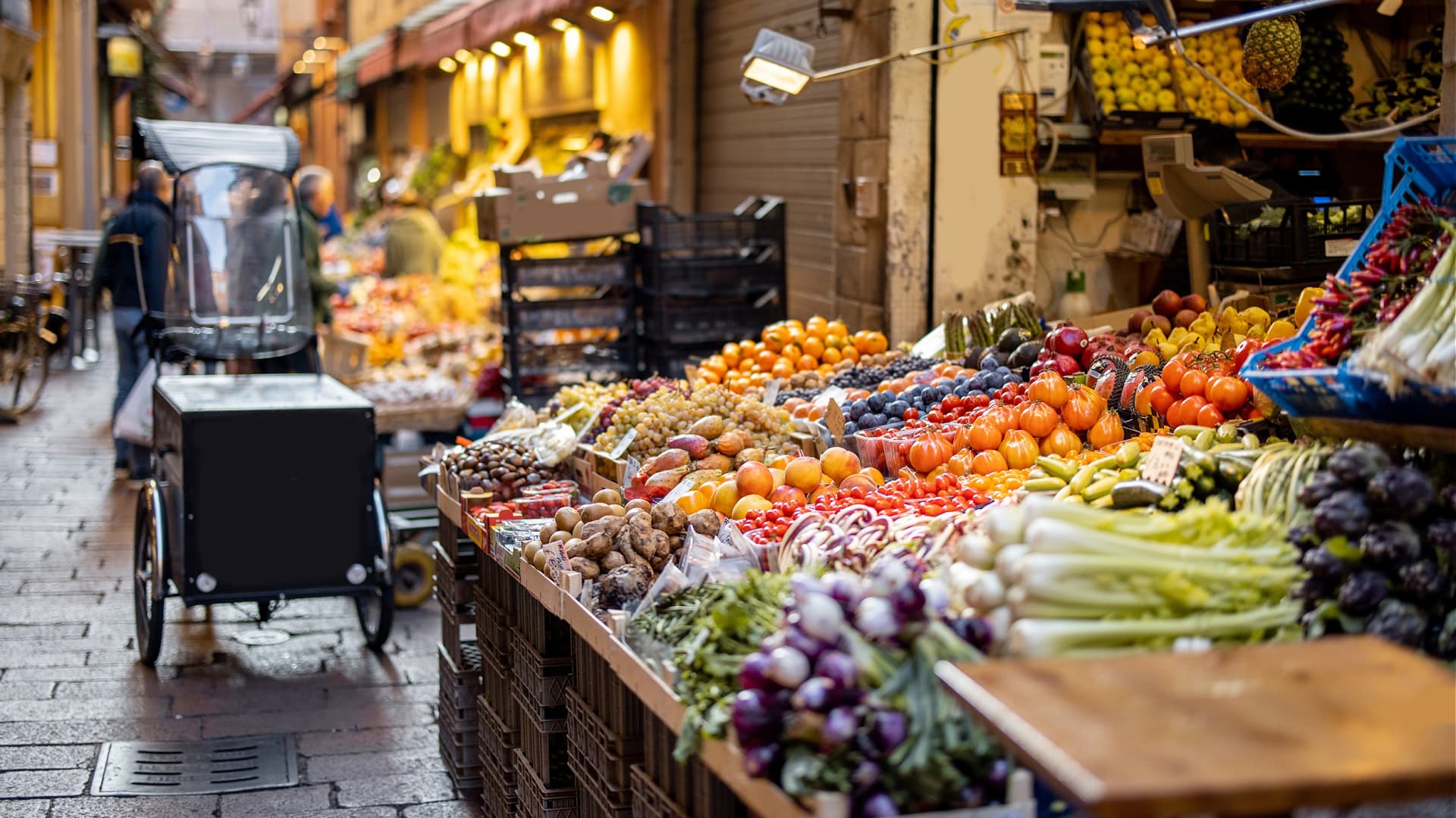 Vibrant display of various fruits and vegetables in a market setting with carts and crates. - Olive Oil Times