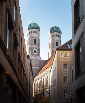 View of the twin towers of Munich's Cathedral framed by surrounding buildings. - Olive Oil Times