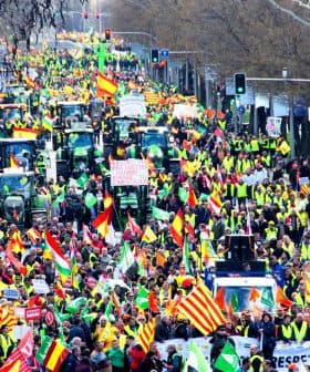 A large crowd of demonstrators with tractors and flags participating in a protest. - Olive Oil Times