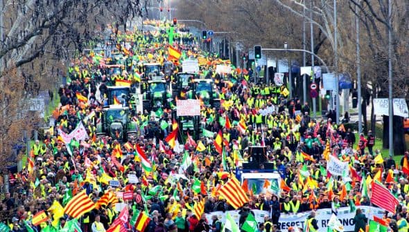 A large crowd of demonstrators with tractors and flags participating in a protest. - Olive Oil Times