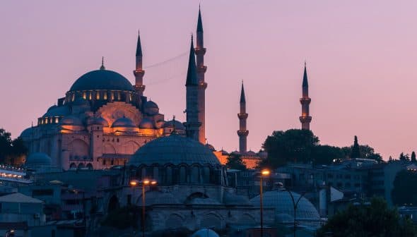 A view of a mosque in Istanbul with multiple minarets during dusk, illuminated by soft lighting. - Olive Oil Times
