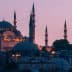 A view of a mosque in Istanbul with multiple minarets during dusk, illuminated by soft lighting. - Olive Oil Times