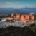 Aerial view of a historic castle surrounded by mountains and greenery. - Olive Oil Times