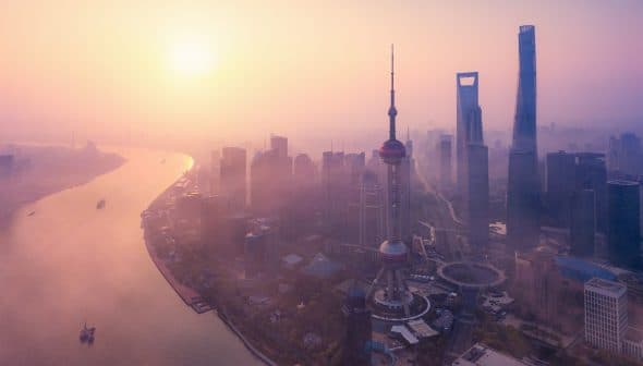 Aerial view of Shanghai skyline featuring the Oriental Pearl Tower and skyscrapers during sunset. - Olive Oil Times