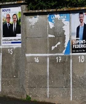 Various political campaign posters displayed on a concrete wall with numbered sections. - Olive Oil Times