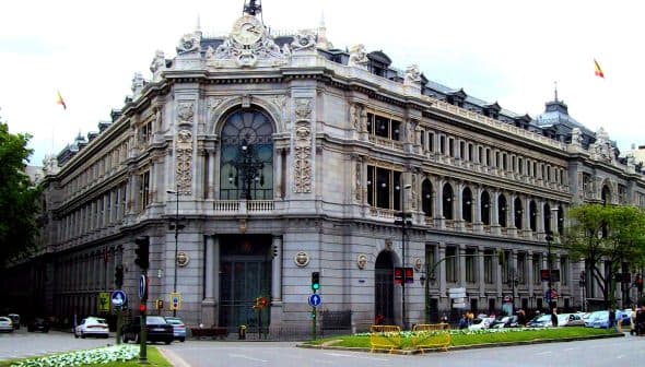 A large historic building in Madrid featuring ornate architectural details and a clock on the facade. - Olive Oil Times