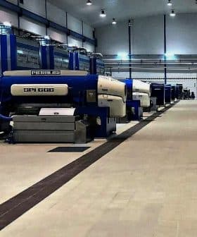 Industrial olive oil processing machines arranged in a facility with blue and white colors. - Olive Oil Times