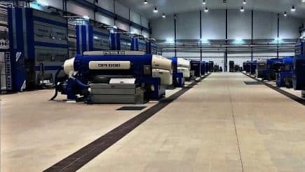 Industrial olive oil processing machines arranged in a facility with blue and white colors. - Olive Oil Times