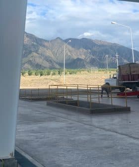 A truck parked in a loading area with mountains visible in the background. - Olive Oil Times