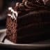 Slice of chocolate layer cake with chocolate frosting and decorative swirls on top. - Olive Oil Times