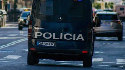 Rear view of a police van with the word 'Policia' on the back, driving on a city street. - Olive Oil Times