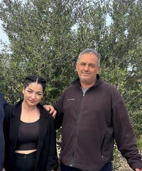 Three individuals standing together in front of an olive tree in an outdoor setting. - Olive Oil Times