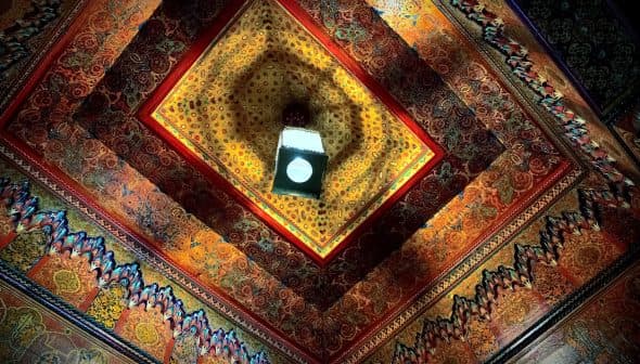 Intricate ceiling design featuring colorful patterns and a central light fixture. - Olive Oil Times