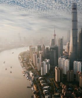 Aerial view of Shanghai skyline featuring tall buildings and a river flowing through the city. - Olive Oil Times