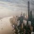 Aerial view of Shanghai skyline featuring tall buildings and a river flowing through the city. - Olive Oil Times