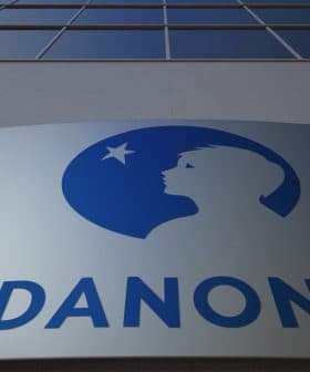 Danone company logo displayed on a building facade with a blue silhouette of a child's profile. - Olive Oil Times
