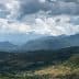 A panoramic view of mountains under a cloudy sky with varying shades of green vegetation. - Olive Oil Times