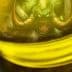 Close-up of a jar containing green liquid with a demon illustration visible inside. - Olive Oil Times
