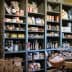 Wooden shelves filled with jars, bottles, and packaged food items in a grocery store. - Olive Oil Times