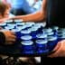 A tray holding multiple blue glasses filled with olive oil being served at an event. - Olive Oil Times
