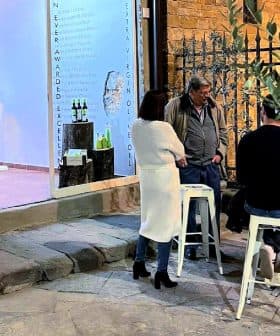 A group of four people gathered around a table outside an art gallery, engaged in conversation. - Olive Oil Times