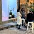 A group of four people gathered around a table outside an art gallery, engaged in conversation. - Olive Oil Times