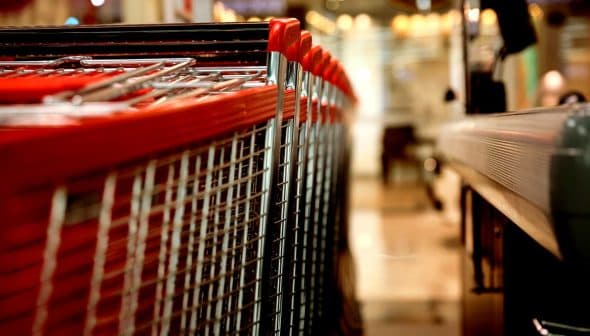 A row of shopping carts with red handles lined up in a retail environment. - Olive Oil Times