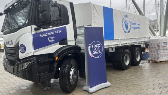 Iveco truck with World Food Programme branding, parked next to a sign for Food for Gaza initiative. - Olive Oil Times