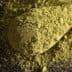 Green powdered substance on a wooden spoon, with loose powder scattered around. - Olive Oil Times