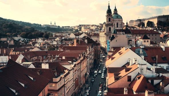 Aerial view of Prague showcasing rooftops and St. Nicholas Church in the background. - Olive Oil Times