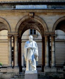 White statue of a historical figure located in the courtyard of the College de France building. - Olive Oil Times