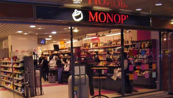 Entrance of a Monop' grocery store featuring shelves stocked with various products. - Olive Oil Times