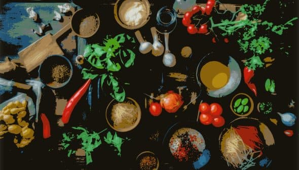 An overhead view of various cooking ingredients including vegetables, herbs, and spices on a wooden surface. - Olive Oil Times