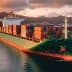 Large container ship loaded with colorful cargo containers navigating calm waters during sunset. - Olive Oil Times