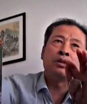 Individual holding a large plastic bottle of oil while speaking during a video call. - Olive Oil Times